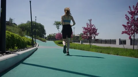 Young woman jogging on a dedicated path, demonstrating commitment to an active 動画素材 310431014