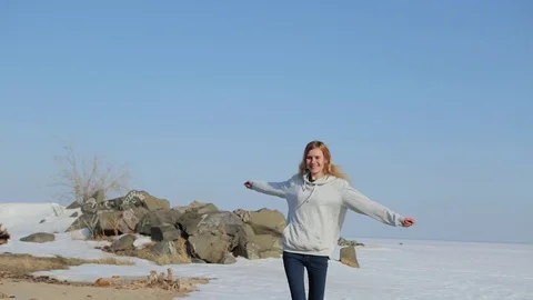 Young woman jumping on the beach.Spring beach with snow Video stock 75009019