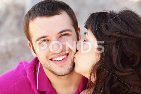 Young woman kissing her boyfriend in cheek Stock Photos