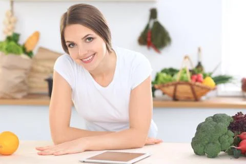 Young woman at the kitchen making online shopping by tablet computer and credit Stock Photos