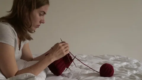 Young woman knitting on a bed Stock Footage 80101367
