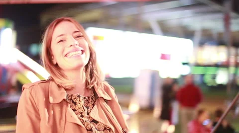Young woman laughing and waving at camera in amusement park Stock Footage 59556316