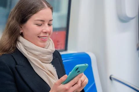 Young Woman Laughing While Using Smartphone on Subway Train, copy space Stock Photos
