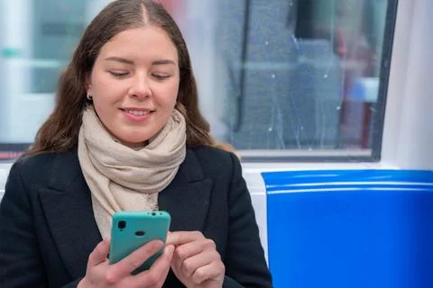 Young Woman Laughing While Using Smartphone on Subway Train, copy space Stock Photos