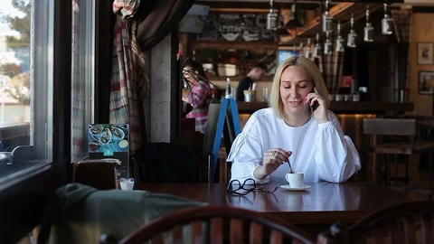 A young woman laughs while talking on the phone in a restaurant Stock-Footage 114395554