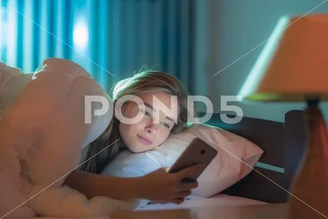 The young woman lay on the bed and phone Stock Photos