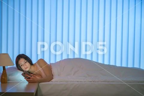 The young woman lay on the bed and phone. Evening night time Stock Photos