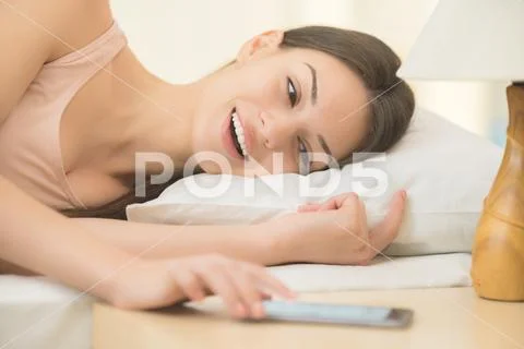 The young woman lay on the bed with phone Stock Photos