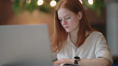 Young woman is learning remote, viewing tutorial on laptop display and writing Stock Footage 172293024