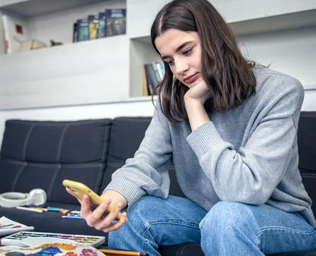 A young woman learns to draw using a video in a smartphone. Stock-Fotos