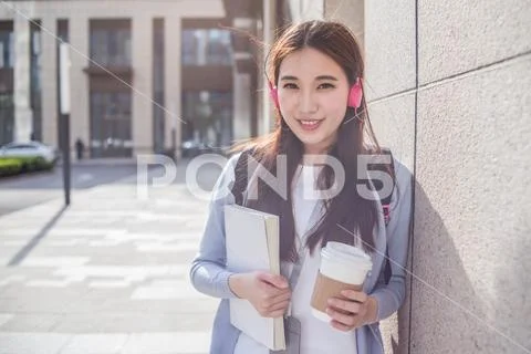 Young Woman Listen Music With Cup Of Coffee And Book In Hands