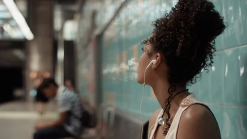 Young woman listening to music while waiting in the metro underground station. Stock Footage