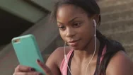 Young Woman Listens To Music And Smiles As She Uses Her Smart Phone Stock Footage