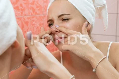 Photograph: Young woman looking and squeeze acne on a face in front of the  mirror. Ugly #140030642