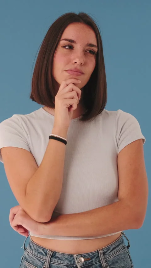 Young woman looking at camera thinks about plan, an idea, isolated on blue Stock Footage 255504938