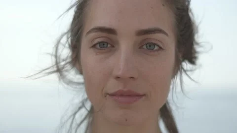 Young woman looking at camera while standing at seaside during sunny day Stock Footage 132047816