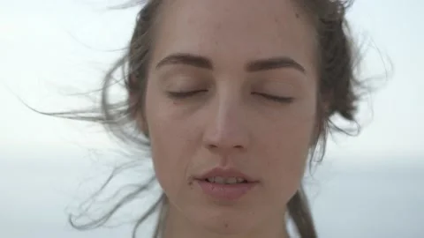 Young woman looking at camera while standing at seaside during sunny day Stock Footage 132048029