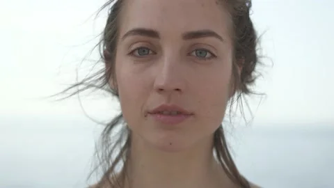 Young woman looking at camera while standing at seaside during sunny day Stock Footage 132048387