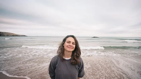 A young woman looking at the camera while standing on the beach. Stock Footage 220357755