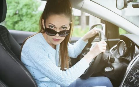 Young woman looking at camera while driving a car Stock Photos