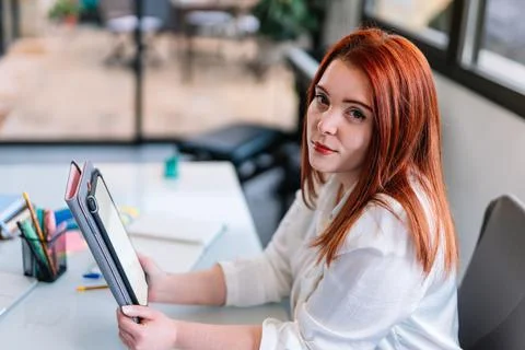 Young woman looking at camera while using tablet at work Stock Photos