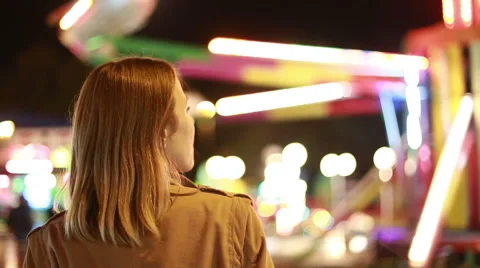 Young woman looking at carousel in amusement park Stock Footage 59556297