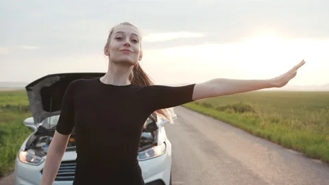 Young woman looking at the engine of breakdown car at the field tries to stop Stock Footage 112746913