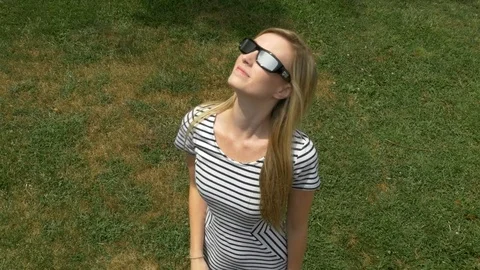 Young woman looking at solar eclipse with special glasses Stock Footage 78493610