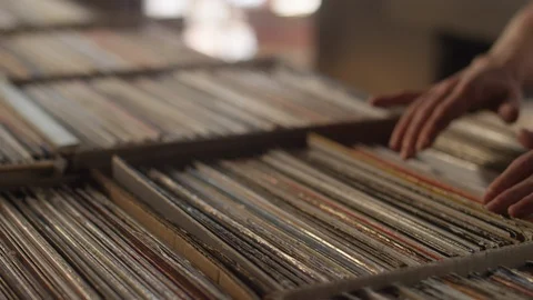 Young woman looking through rows of vinyl records in a record store Video stock 122579408