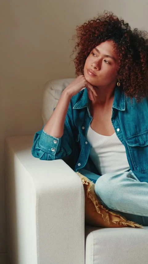 Young woman looking through window while relaxing on sofa Stock Footage 269165076