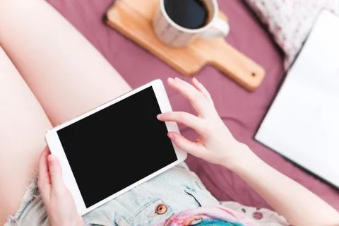 Young woman lying in bed with digital tablet Stock Photos