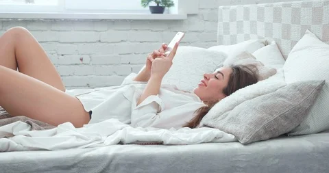 Young Woman lying on bed using Smartphone, Social media browsing, online having Stock Footage 127399969