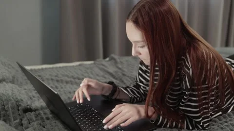 Young woman lying on bed using laptop 動画素材 317757547