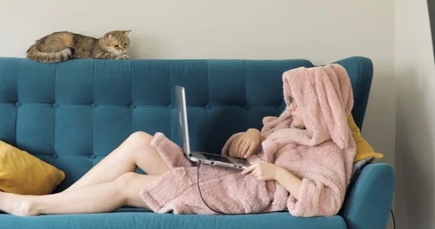 Young woman lying on couch using laptop notebook looking at screen typing Video stock 127561475