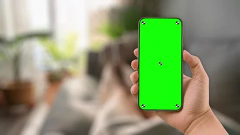 Young woman lying on couch using smartphone with green mock up screen chroma key Video stock 306170106