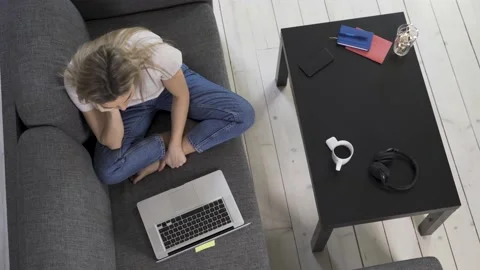 Young woman lying down on sofa and having video call Video stock 233434618