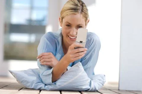 Young woman lying on floor, using mobile phone Stock Photos