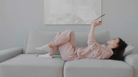Young woman lying on sofa tapping tablet reading news browsing social networks. Stock Footage 149142741