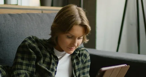 Young woman is lying on sofa, using tablet computer, close up Stock Footage 114643673