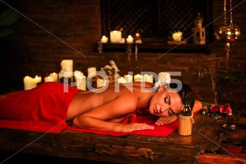 Young woman lying on wooden spa bed in massage spa salon. Stock Photos