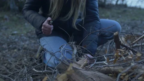 Young woman making fire while camping outdoors, in an alpine wilderness - Stock Footage 137601201