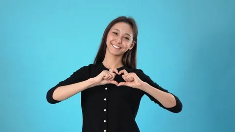 Young Woman Making Heart Shape With Hands on Blue Background Vídeo Stock 346111478