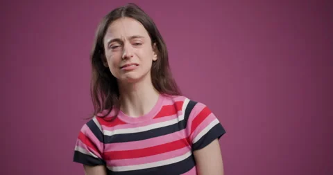 Young woman making a sad expression against a plain pink background Stock Footage 346660917