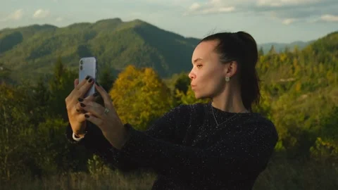 Young woman making selfies using mobile phone standing on top of mountain peak Stock Footage 269042289