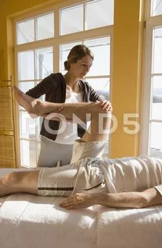 Young woman massaging man's leg Stock Photos