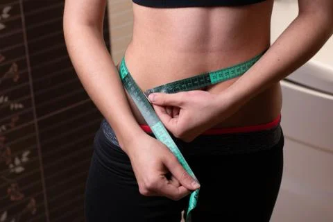 Young woman measuring her thin waist with a tape measure Stock Photos