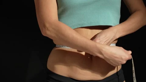 Fit and healthy young lady measuring her waist with a tape measure