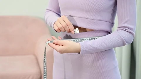 Young woman measuring waist after weightloss. Diet and healthy eating concept Stock Footage