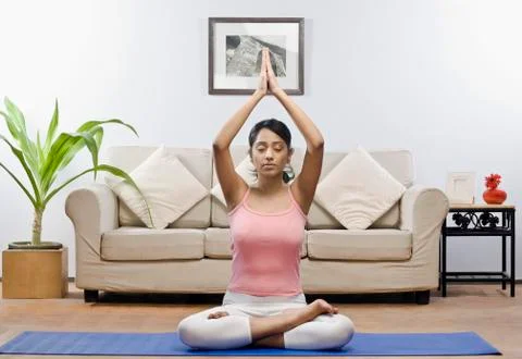 Young woman meditating in a living room Stock Photos