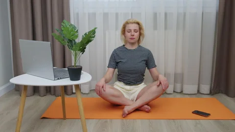 A young woman meditating while sitting on a mat indoors. Stock Footage 266416594
